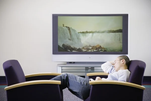 Young Asian man in chair next to television