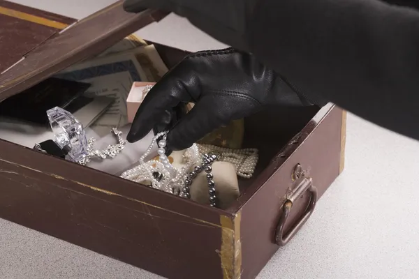 Close up of gloved hands taking jewels out of box