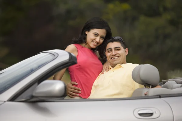 Hispanic couple hugging in convertible car