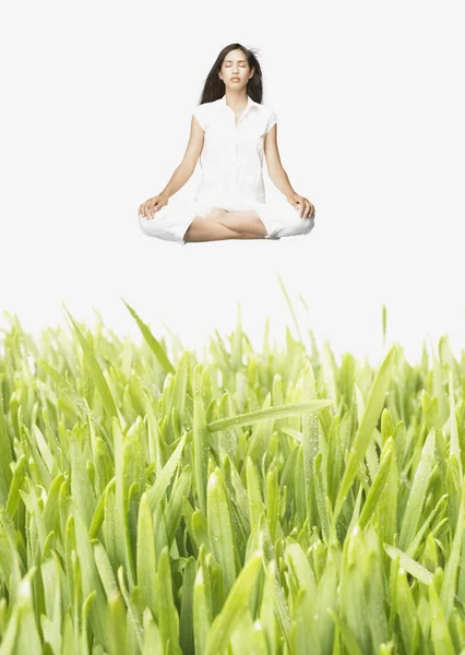 Young meditating woman levitating above tall grass