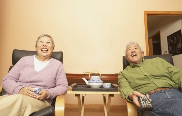 Senior Asian couple having tea while watching television