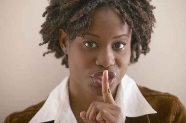 Young African woman with index finger up to pursed lips
