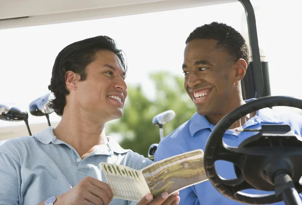 Two men smiling at each other in golf cart