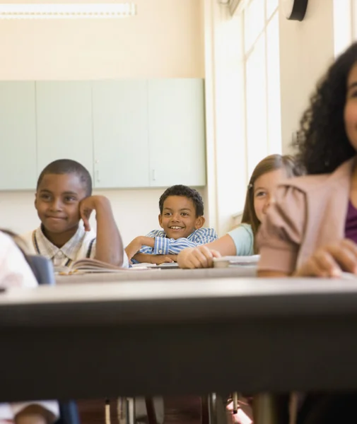 Young students smiling at desks in classroom