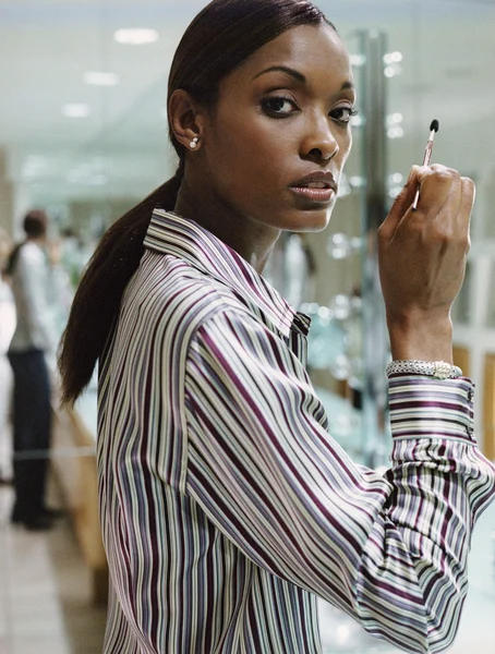 African American woman applying makeup