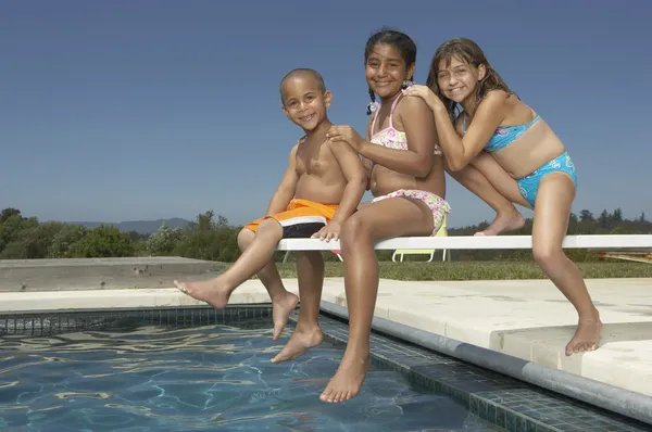 Young children smiling for the camera on a diving board