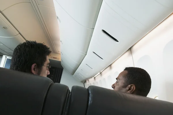 Two men talking on airplane