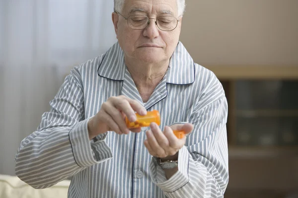 Older man shaking out pills into his hand