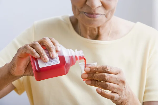 Close up of senior African woman pouring medication into cup
