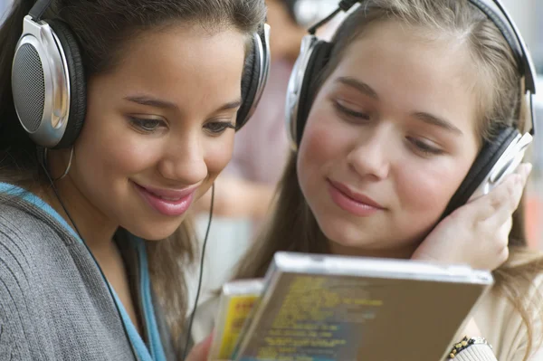 Close up of two teenage girls with headsets listening to music
