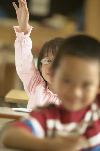 Young girl raising hand in classroom