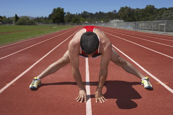 Male track runner stretching