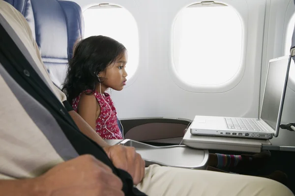 Profile of young girl with laptop on airplane