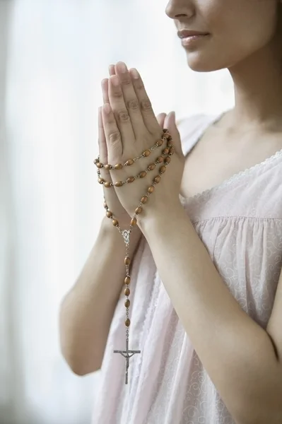 Young woman praying with rosary beads