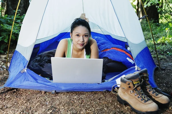 Woman using laptop in tent