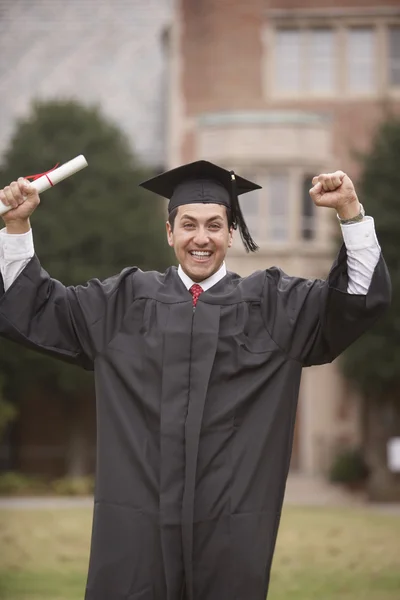 Portrait male graduate in cap with diploma and arms raised
