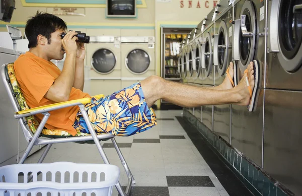 Man with lawn chair and binoculars at laundromat