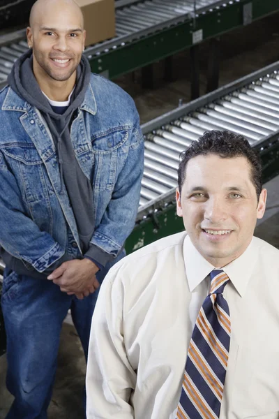 Two men standing next to conveyor belts