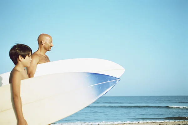 Father and son carrying surfboards