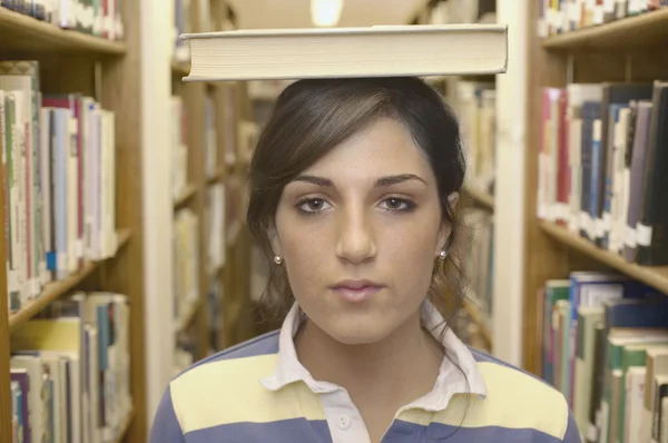 Close up of teenage girl with book on head