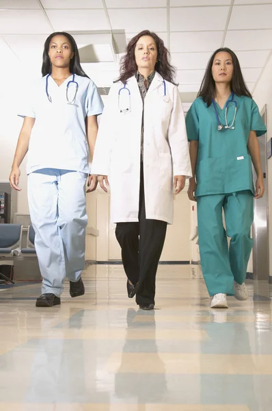 Female nurses and doctors walking through hospital