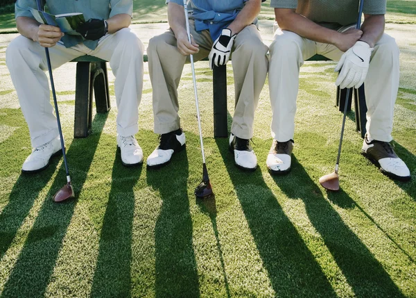 Golfers sitting on bench