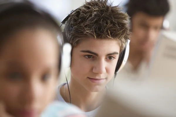 Teenagers in computer lab wearing headsets — Stock Photo #23237140