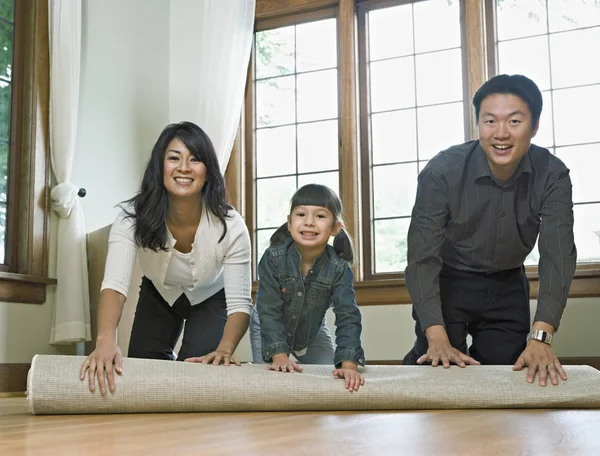 Family unrolling a rug in empty room