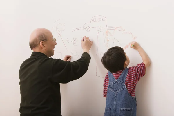 Elderly man and grandson drawing on the wall