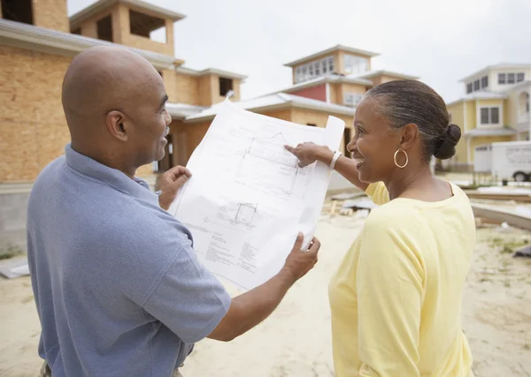 African American couple reading house plans at construction site