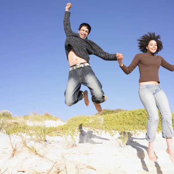 Young couple jumping off a sand dune
