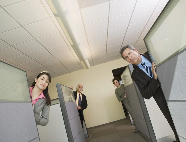 Businesspeople peeking out of office cubicles