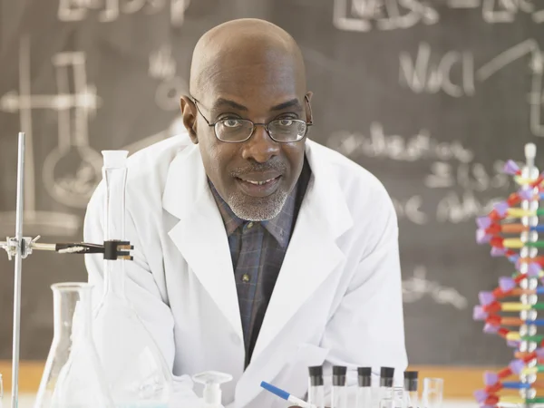 African male science teacher in front of the blackboard