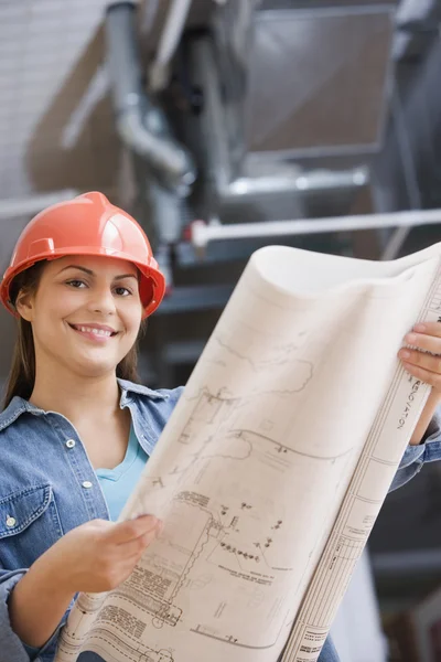Hispanic female construction worker looking at blue prints