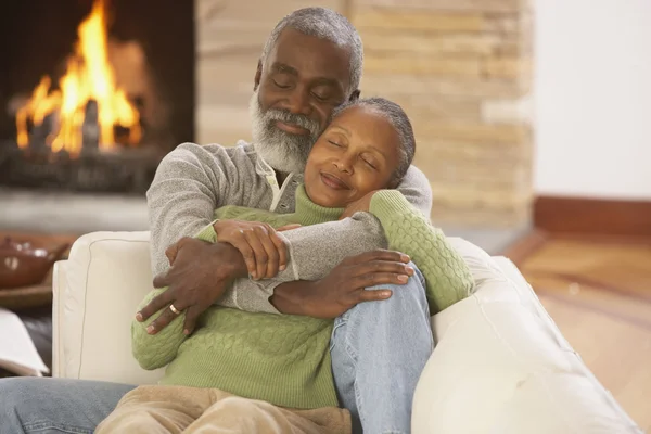 Senior African couple hugging on the sofa