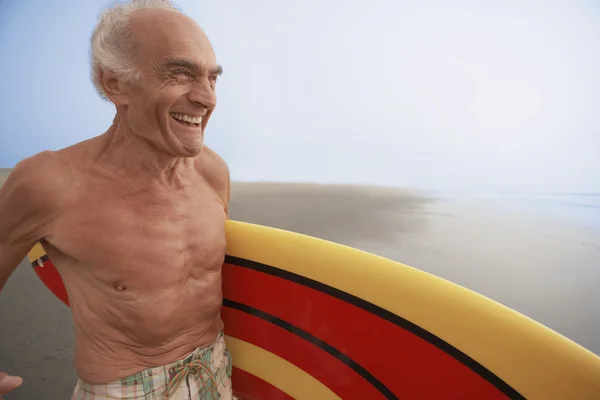 Senior man with surfboard at the beach