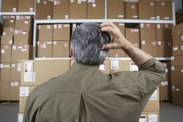 Businessman in warehouse scratching his head