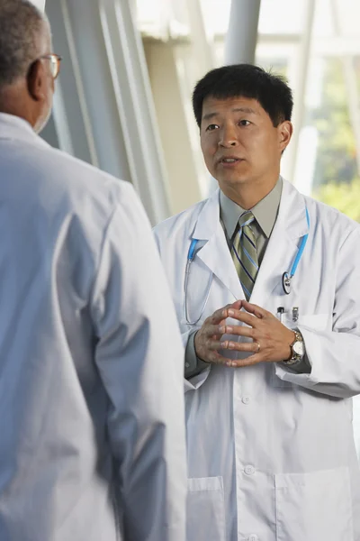 Middle-aged Asian doctor talking to co-worker