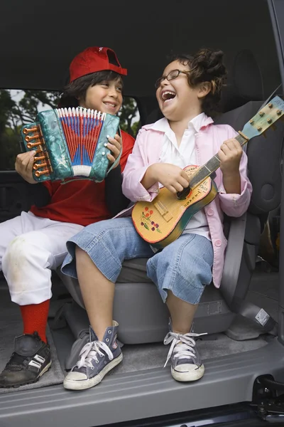Brother and sister playing toy instruments in back of car