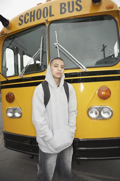 Young man with backpack next to school bus