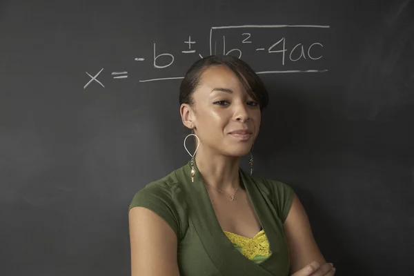 African female student next to math problem on blackboard