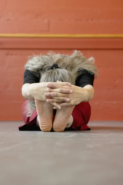 Middle-aged woman stretching next to ballet bar