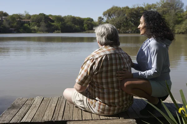 Couple sitting on wooden dock looking at water