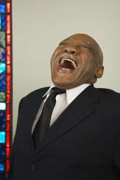 Senior African man laughing next to stained glass window