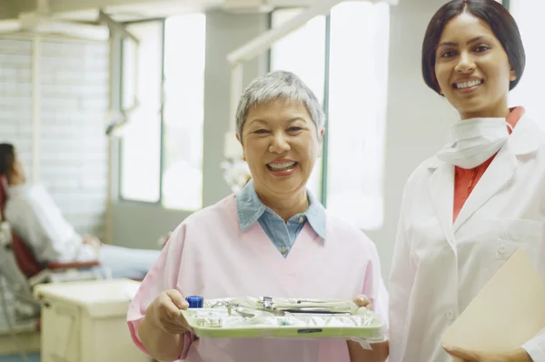 Indian female dentist and senior Asian female dental assistant smiling