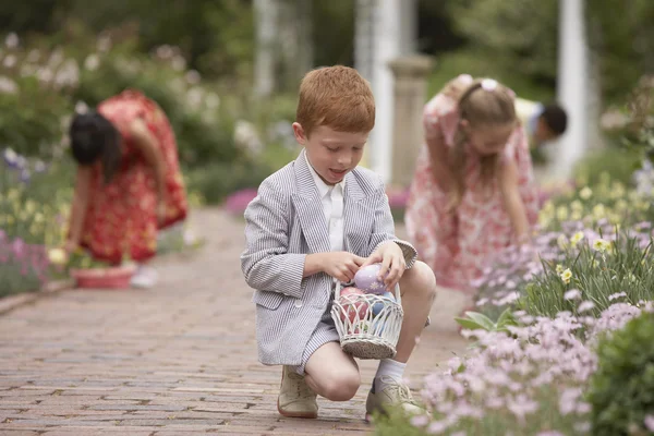 Children gathering Easter eggs in garden