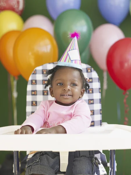 African baby in high chair wearing party hat