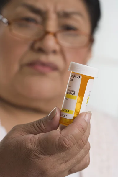 Senior Hispanic woman looking at medication bottle