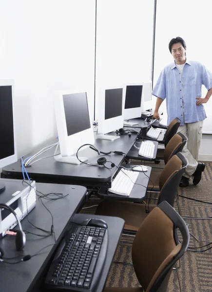 Young Asian man standing next to computer stations