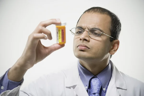 Indian male pharmacist looking at medication bottle
